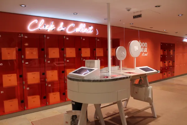 Automated Click & Collect area at a Bonprix smart retail store, featuring orange RFID-enabled pickup lockers and digital kiosks for a seamless omnichannel shopping experience.
