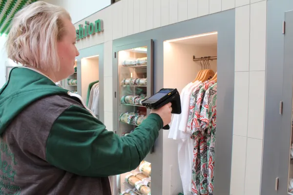 A retail employee using a handheld RFID scanner to perform a real-time inventory count of Heineken merchandise, reducing stock-taking time from days to minutes.